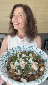 kobieta trzymająca w ręce miskę z daniem z bobem, koperkiem i migdałami